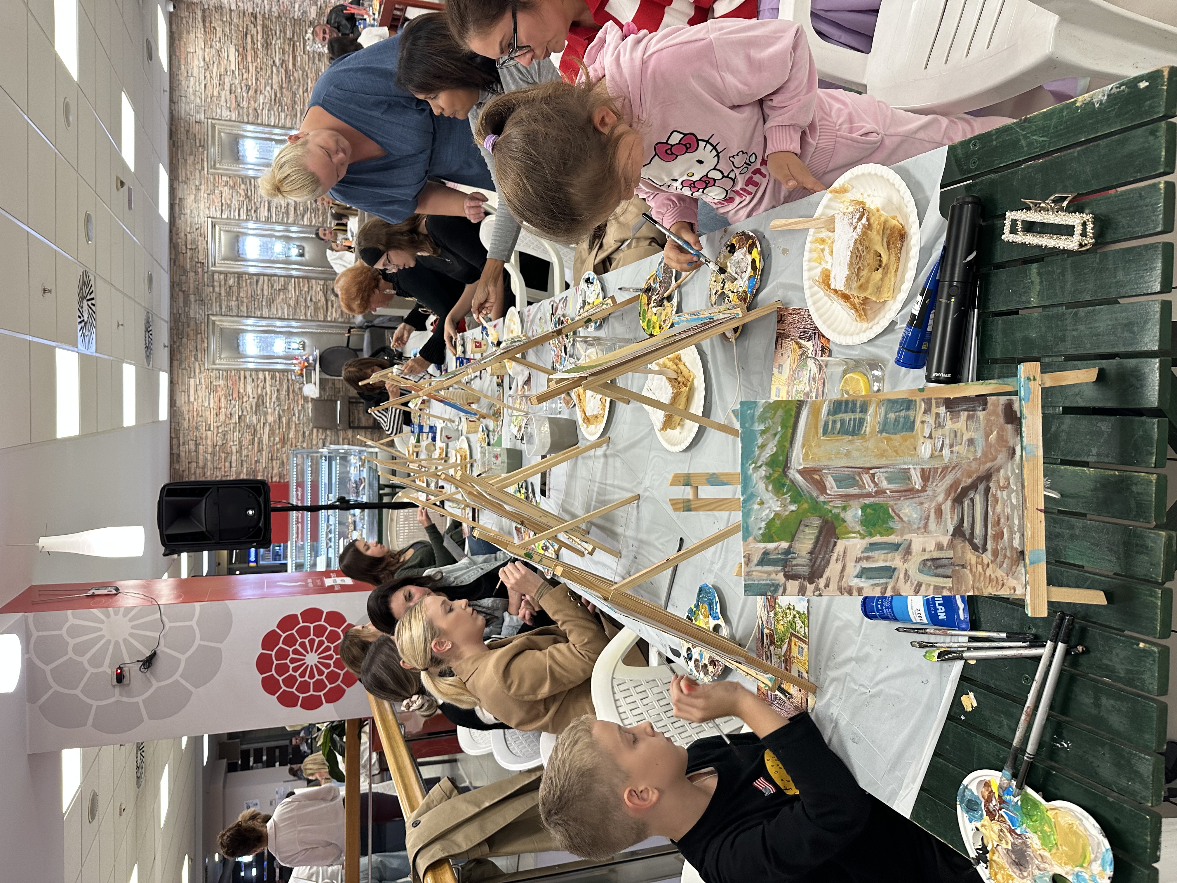 Adults and children painting at a long table during a workshop in a hospitality venue